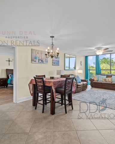 Open-plan living room with dining area, brown leather furniture, turquoise curtains, and views of landscaped grounds