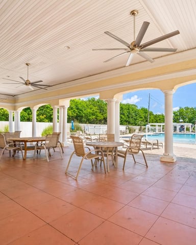 Covered patio with ceiling fans, lounge chairs, and view of swimming pool and grounds beyond
