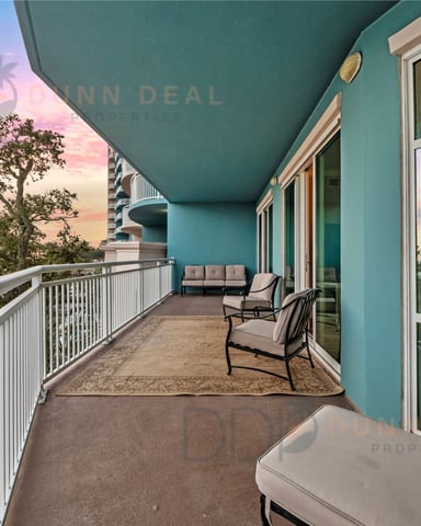 Turquoise balcony with lounge chairs overlooking sunset sky, ocean, and tropical landscape