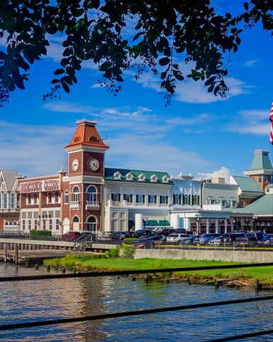 Waterfront row of colorful Victorian buildings with clock tower and American flag under blue sky