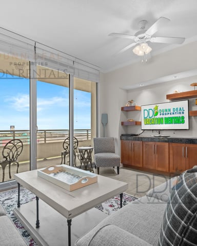 High-rise condo living room with floor-to-ceiling windows, city view, ceiling fan, TV, and modern furnishings