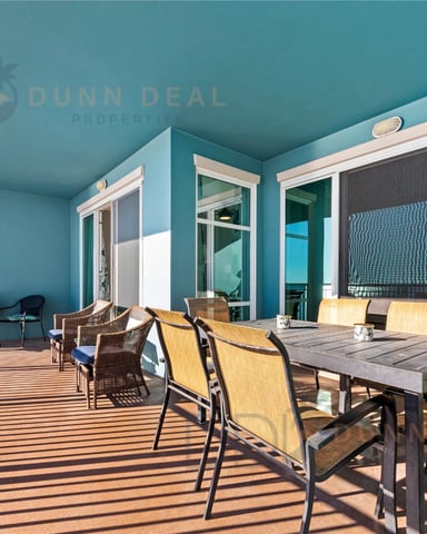 Turquoise high-rise balcony with dining table, lounge chairs, and ocean view